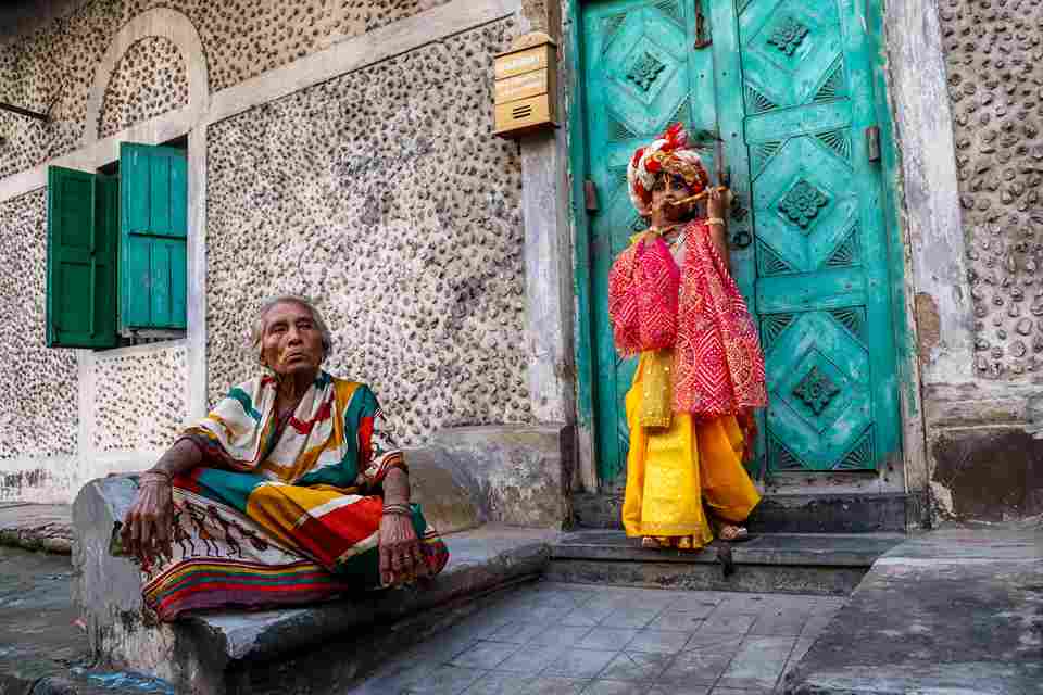 Photo by Soumalya Das: https://www.pexels.com/photo/child-in-traditional-festive-hindu-costume-standing-next-to-an-elderly-woman-at-the-entrance-to-the-house-18299128/